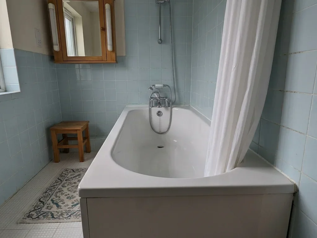 Un homme âgé hésitant devant une baignoire haute sans barre de maintien sécurisée.