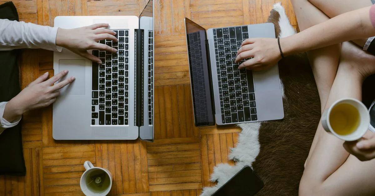 Deux femmes utilisant des ordinateurs portables avec des tasses de thé, illustrant le mode de vie du travail à distance.